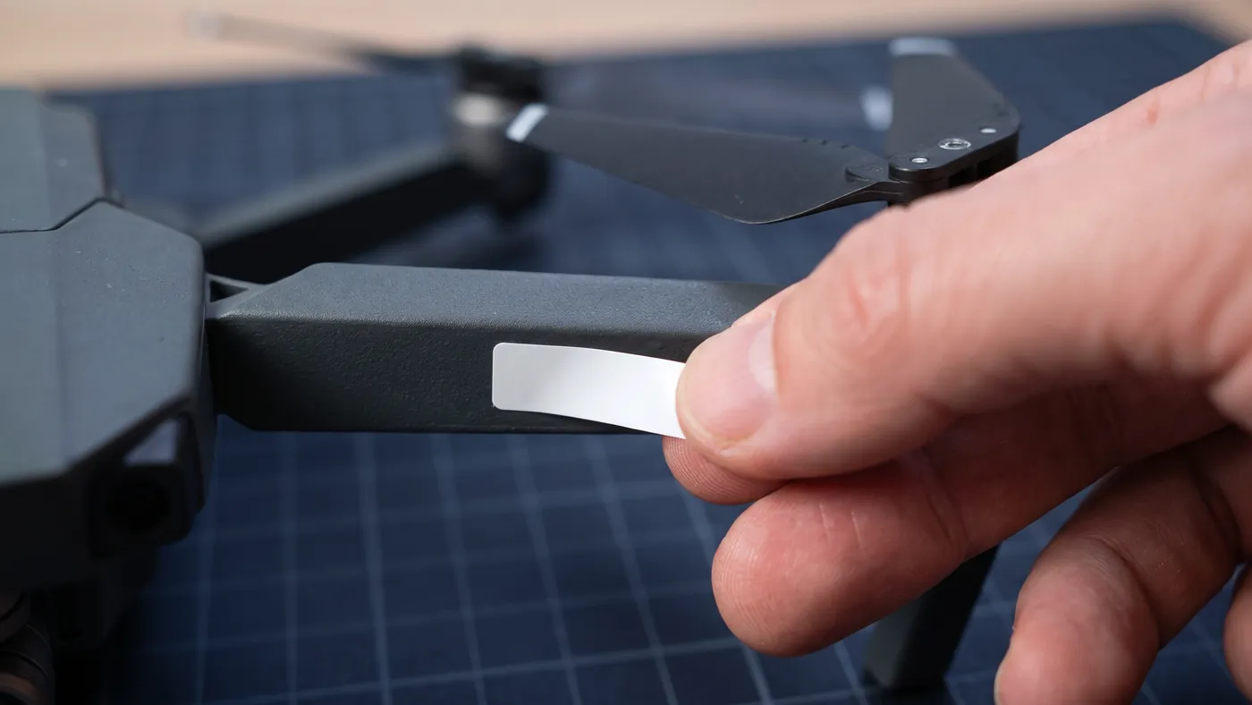 Etiqueta de identificação sendo colada no braço do drone para exibir o número do cadastro no SISANT